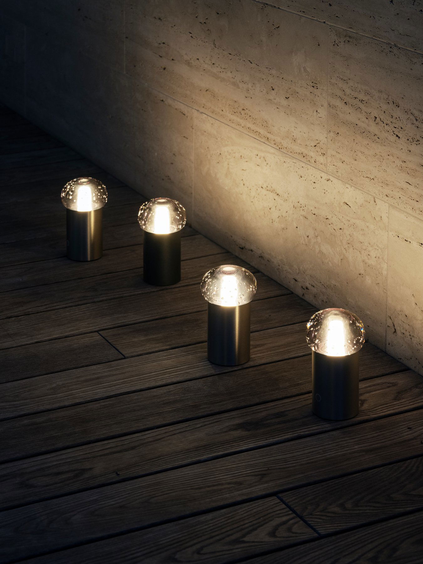 Moderne Außenbeleuchtung mit Glasdomeformen, die die Holzterrasse bei Nacht beleuchten.