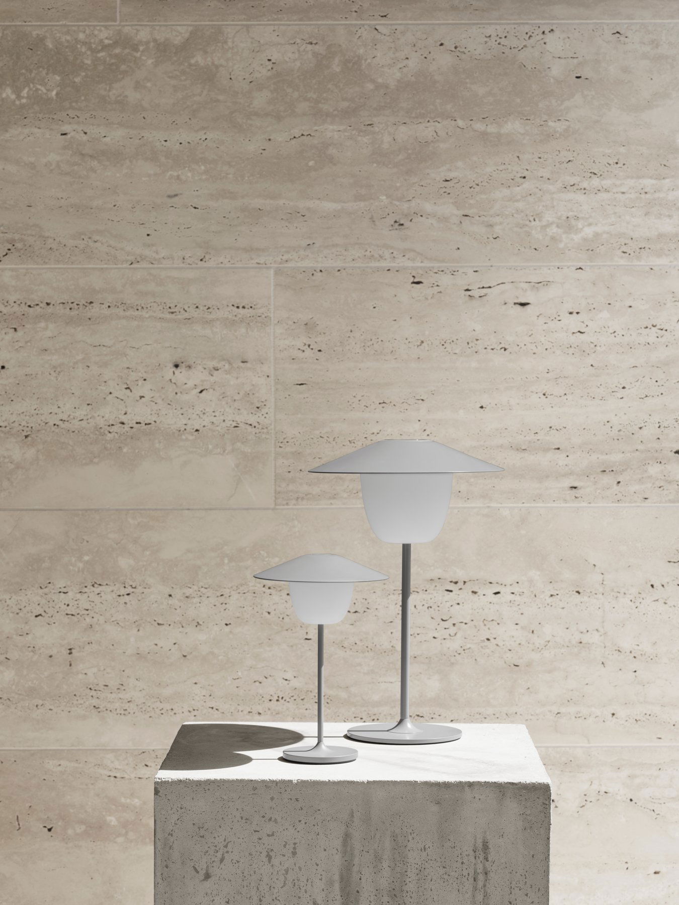 Moderne Tischlampen mit minimalistischem Design auf einem strukturierten Stein-Hintergrund.