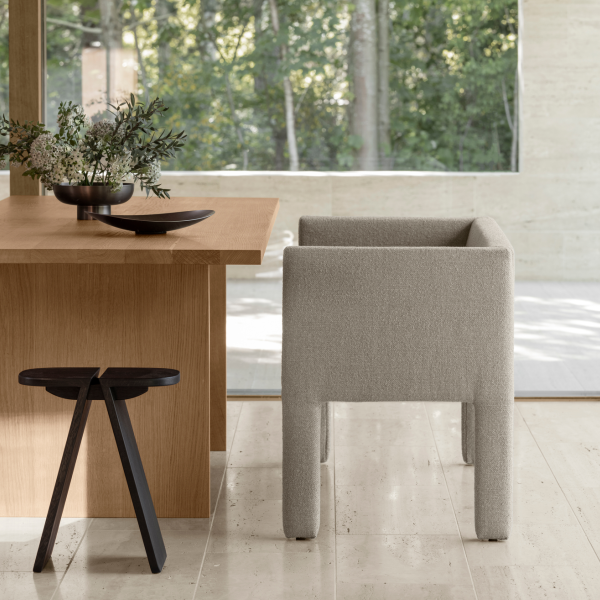 Modern dining area featuring a cozy chair and wooden table with a serene outdoor view.