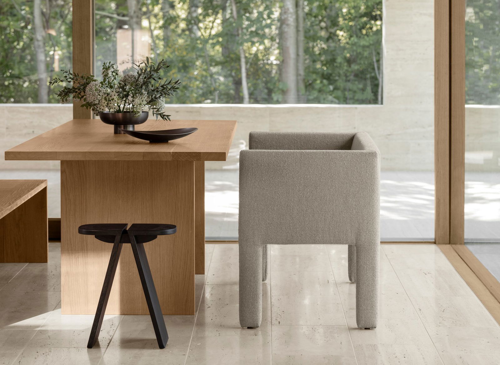 Modern dining area featuring a cozy chair and wooden table with a serene outdoor view.