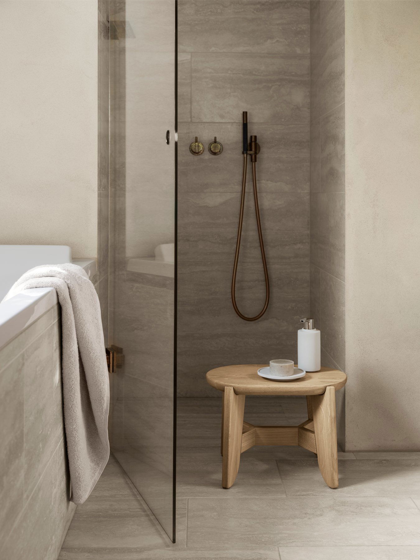 Elegant modern bathroom featuring a glass shower, wooden stool, and minimalist decor.