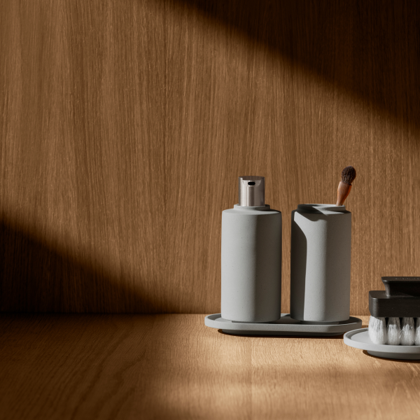 Minimalist bathroom accessories arranged on a wooden surface with soft, natural lighting.