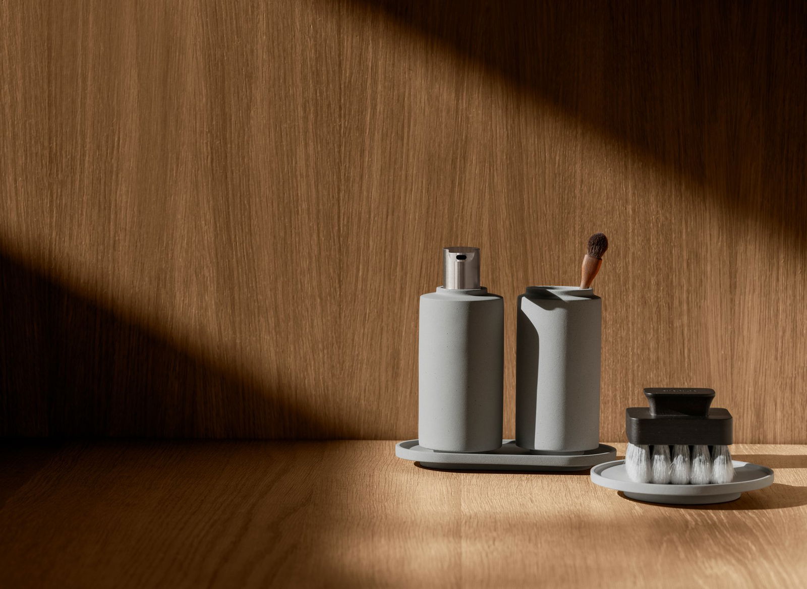 Minimalist bathroom accessories arranged on a wooden surface with soft, natural lighting.