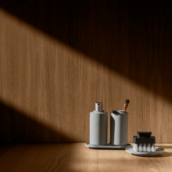Minimalist bathroom accessories on a wooden surface with dramatic lighting.