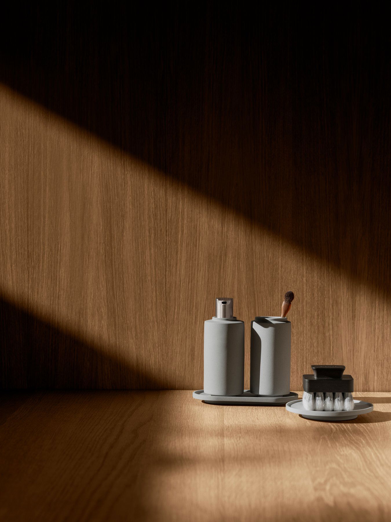 Minimalist bathroom accessories on a wooden surface with dramatic lighting.