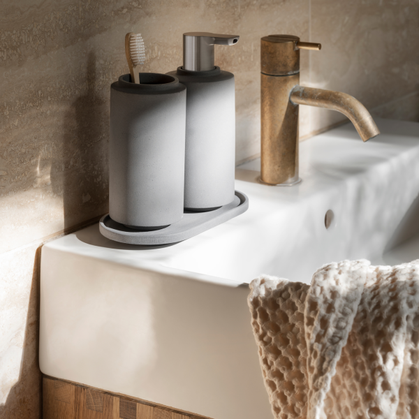 Stylish gray bathroom accessories on a modern sink with sunlight streaming in.