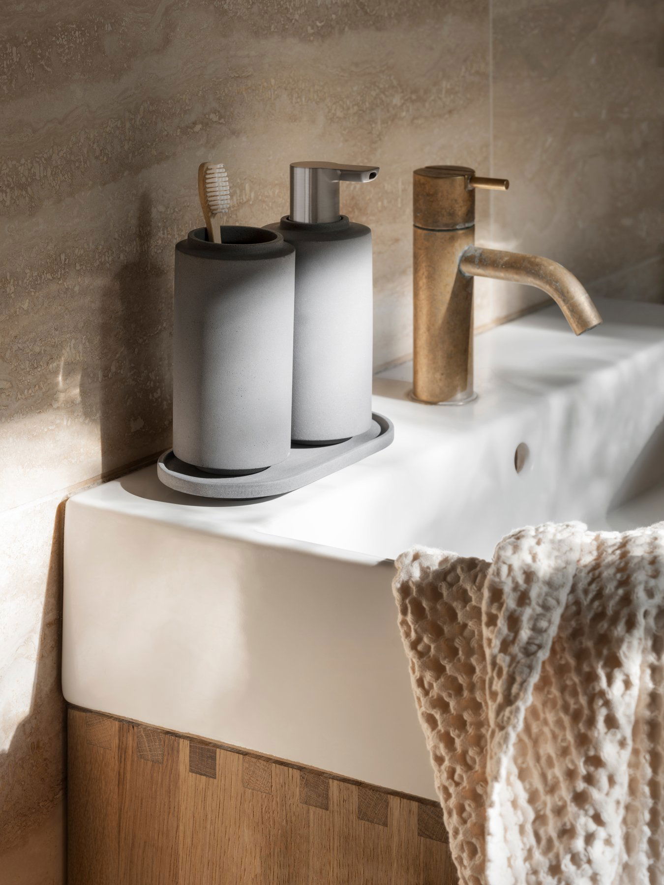 Stylish gray bathroom accessories on a modern sink with sunlight streaming in.