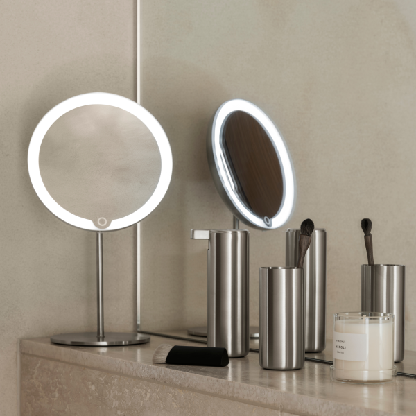 Moderner Schminkbereich mit beleuchteten Spiegeln und eleganten, metallischen Schönheitsaccessoires.