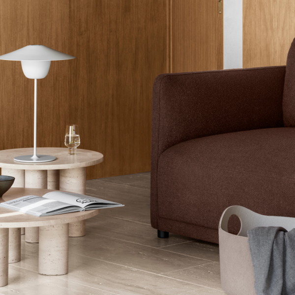 Moderne Wohnzimmer-Szene mit einem braunen Sofa, einer minimalistischen Lampe und einem stilvollen Couchtisch.