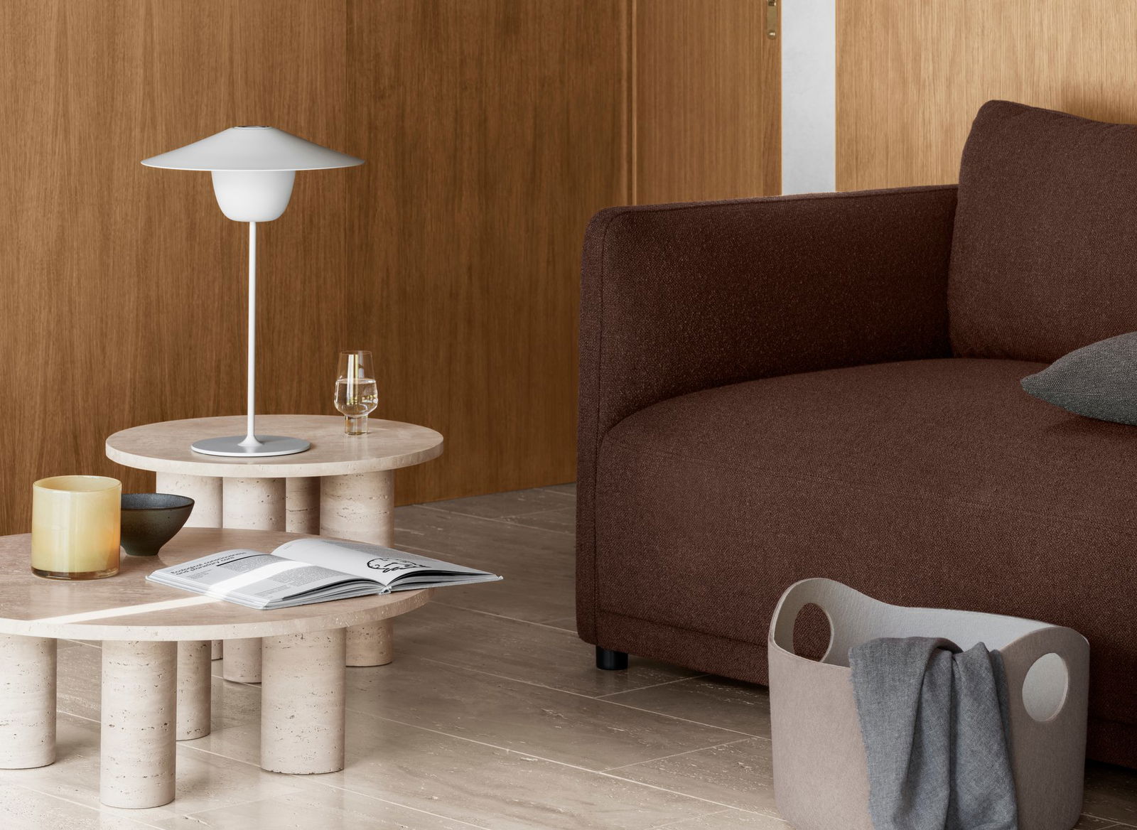 Moderne Wohnzimmer-Szene mit einem braunen Sofa, einer minimalistischen Lampe und einem stilvollen Couchtisch.