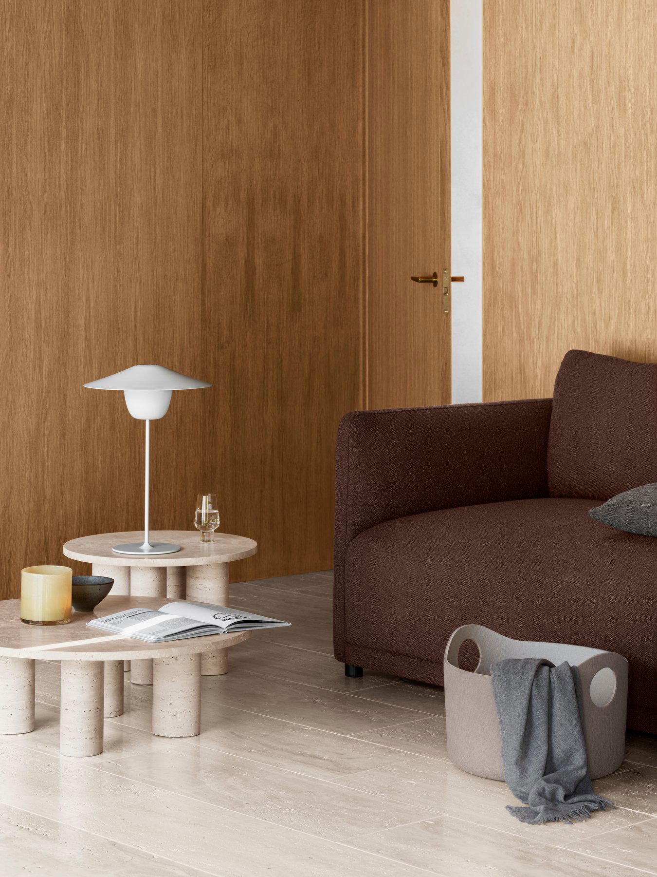 Moderner Wohnraum mit braunem Sofa, minimalistischer Lampe und stilvoller Dekoration an der Holzwand.