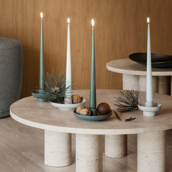 Stylish candles on modern tables with decorative plates and natural elements.