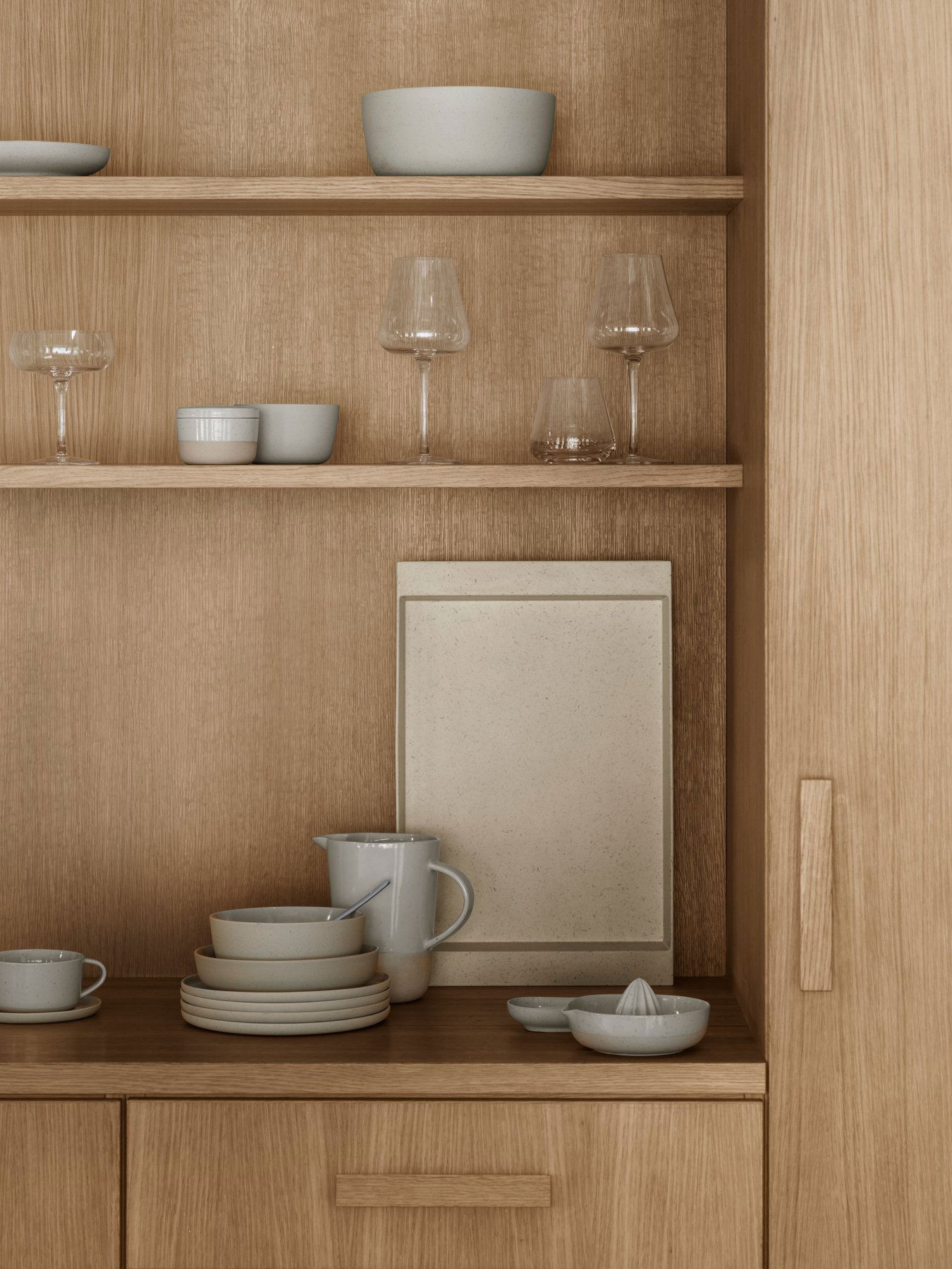 Minimalistische Kücheregale, die elegantes Geschirr und Glaswaren vor einem Holz-Hintergrund präsentieren.
