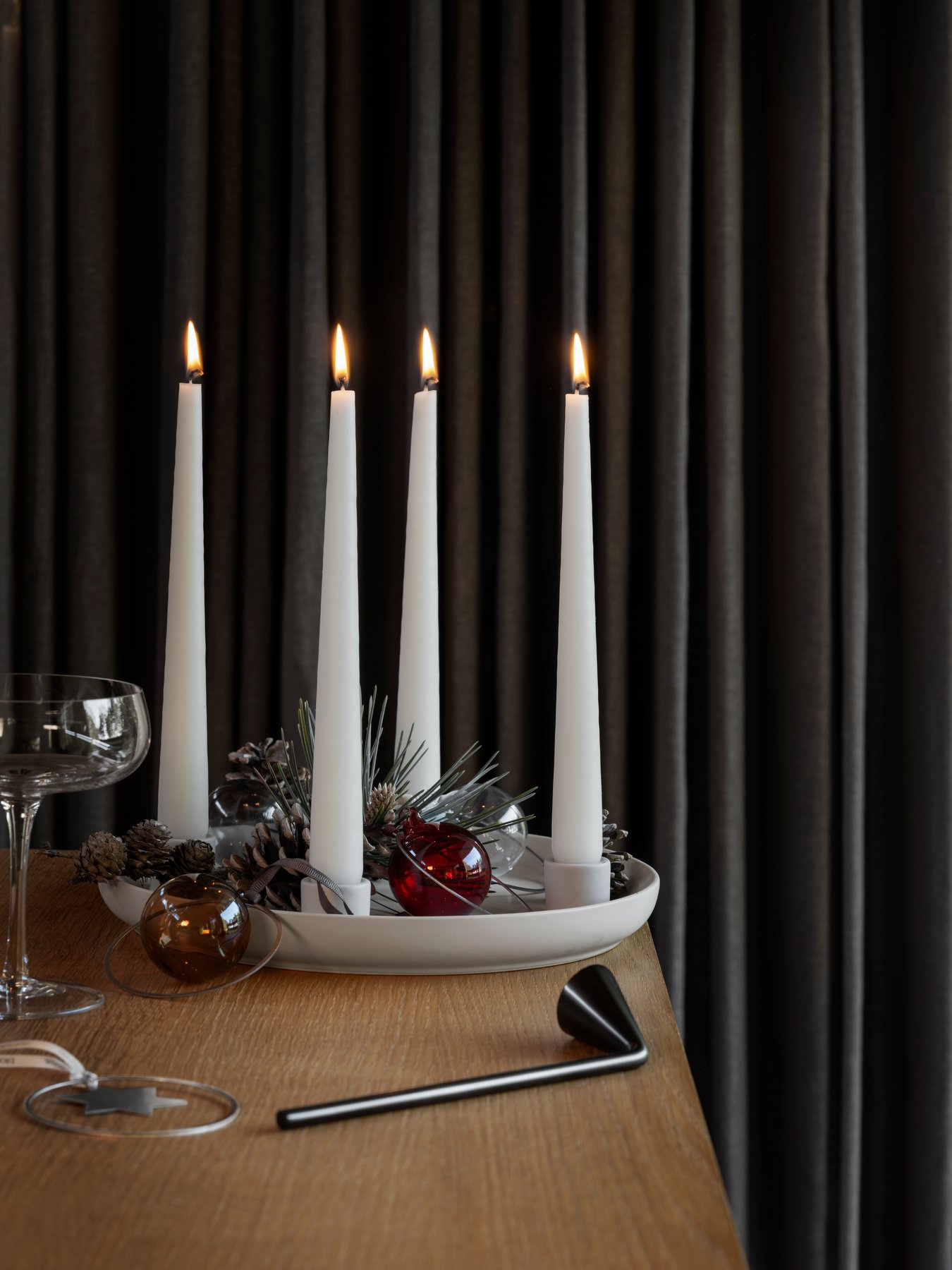 Elegant Christmas centerpiece with lit candles, pinecones, and decorative ornaments.