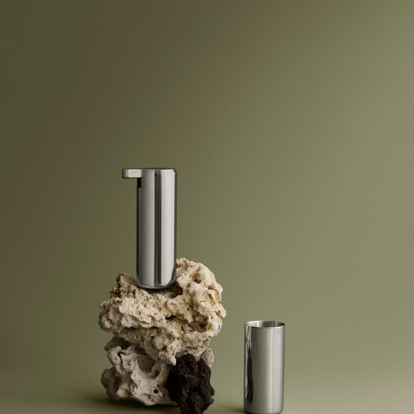 Stylish metallic container on textured stones against a muted green background.