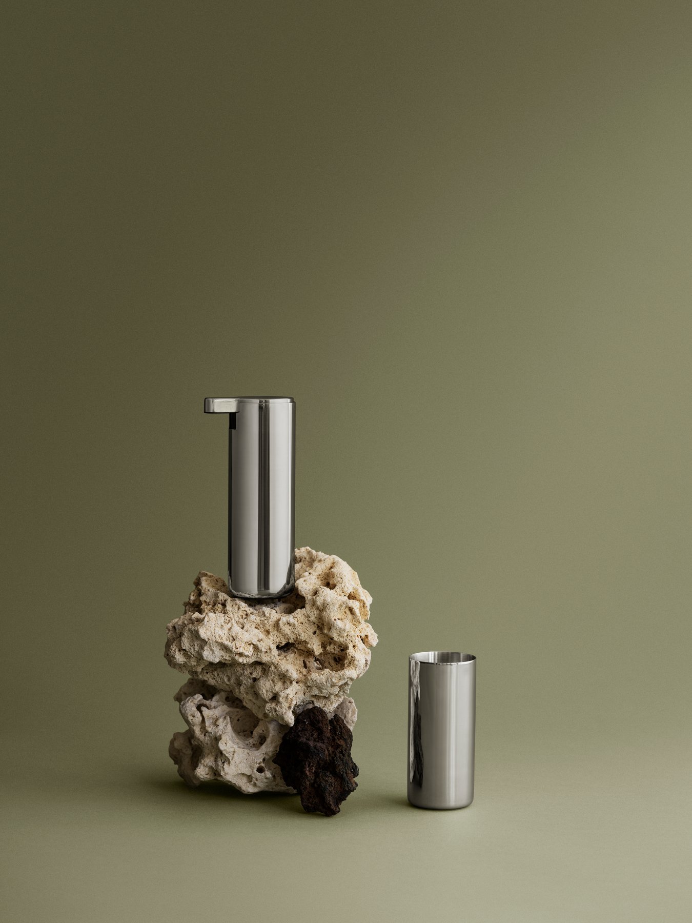 Stylish metallic container on textured stones against a muted green background.