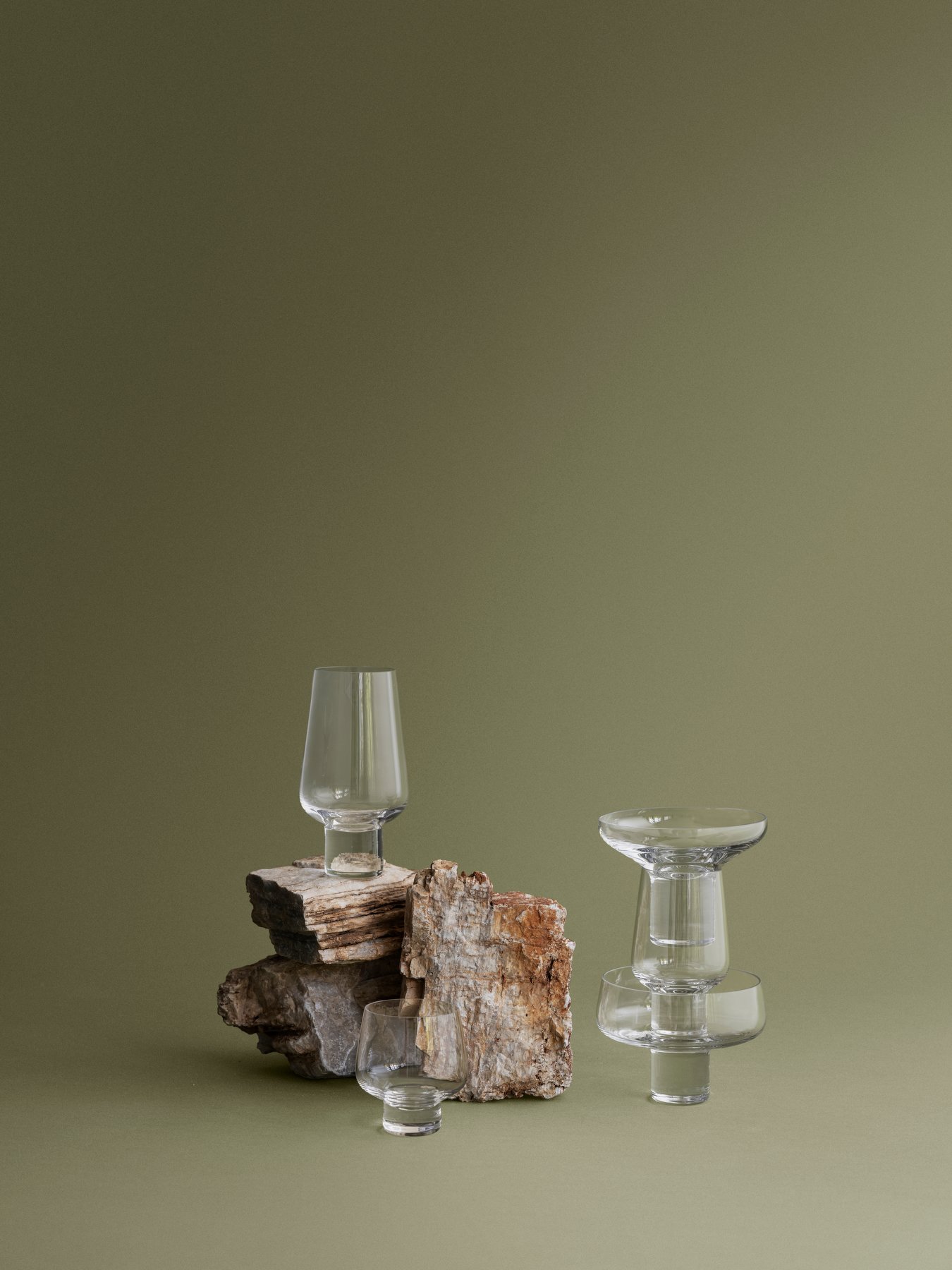 Elegantes Glasgeschirr auf natürlichem Stein, vor einem gedämpften grünen Hintergrund präsentiert.