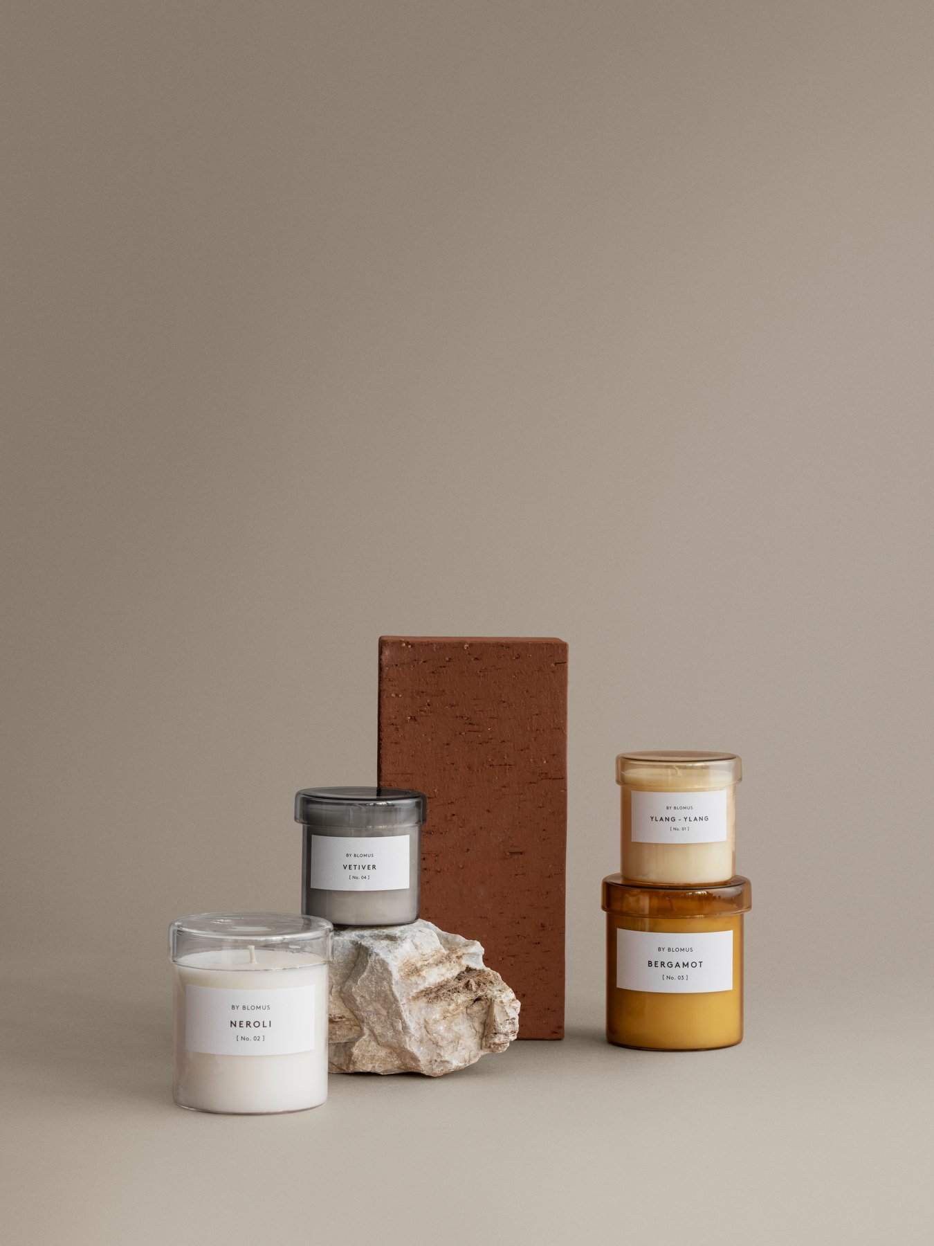 Stilvolle Duftkerzen in Gläsern mit erdigen Tönen und minimalistischen Etiketten auf einem neutralen Hintergrund.