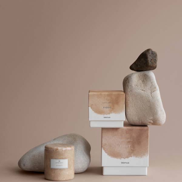 Natural stone and fig-scented products displayed on a soft beige background.