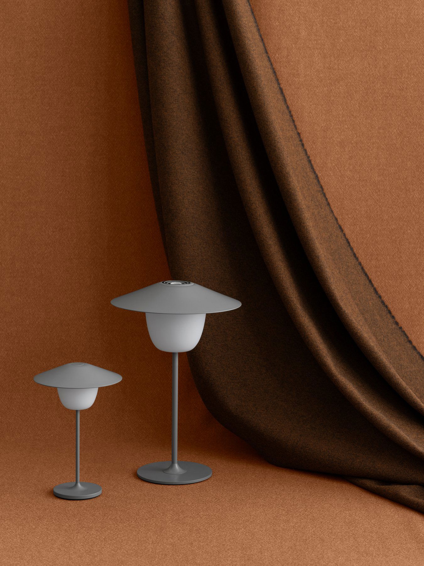 Stylische graue Lampen neben einem strukturierten braunen Vorhang für moderne Inneneinrichtung.