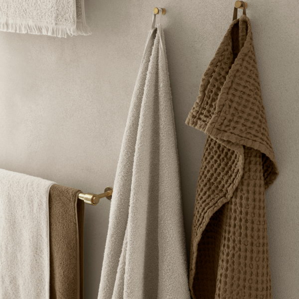 Weiche, stilvolle Handtücher hängen an Wandhaken in einem modernen Badezimmer.