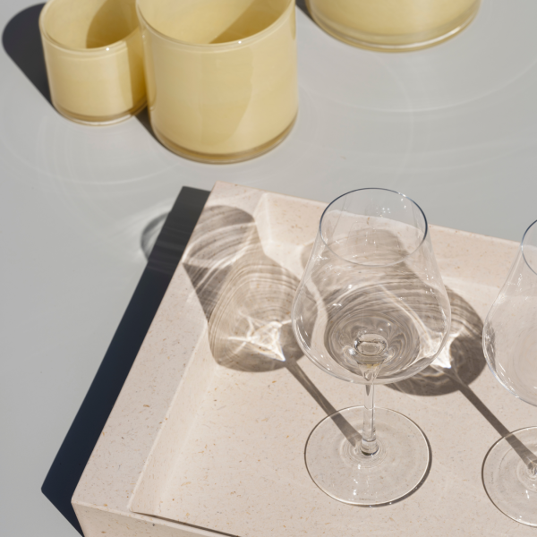 Elegantes Glaswaren auf einem minimalistischen Tablett mit sanften Schatten und zeitgenösslicher Keramik.