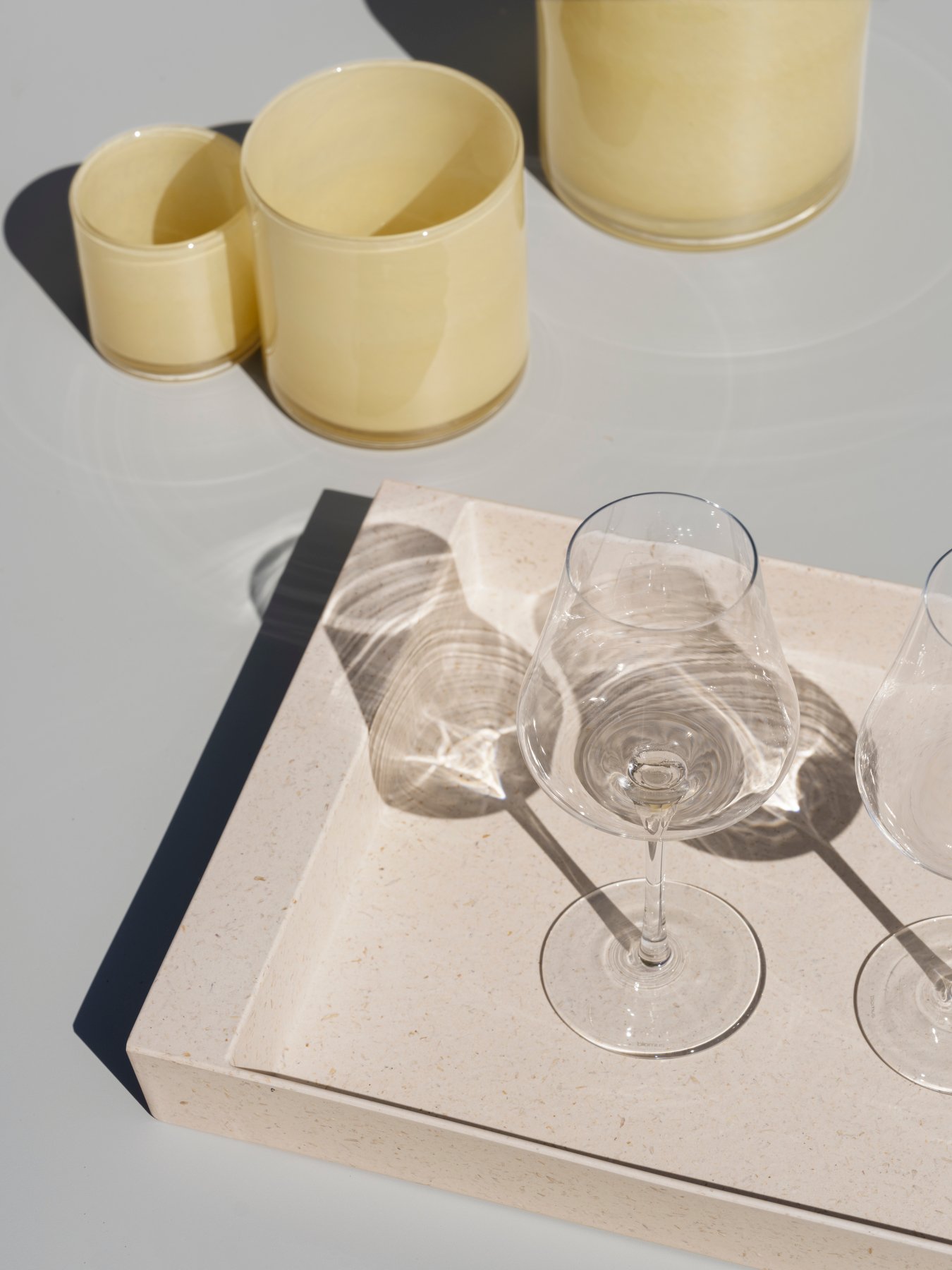 Elegantes Glaswaren auf einem minimalistischen Tablett mit sanften Schatten und zeitgenösslicher Keramik.