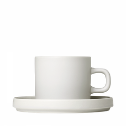 Minimalist white ceramic cup and saucer against a black background.