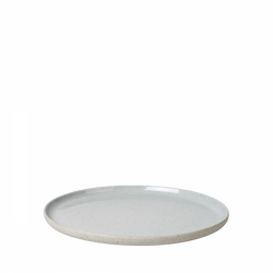 Round white ceramic plate with speckled texture on a black background.