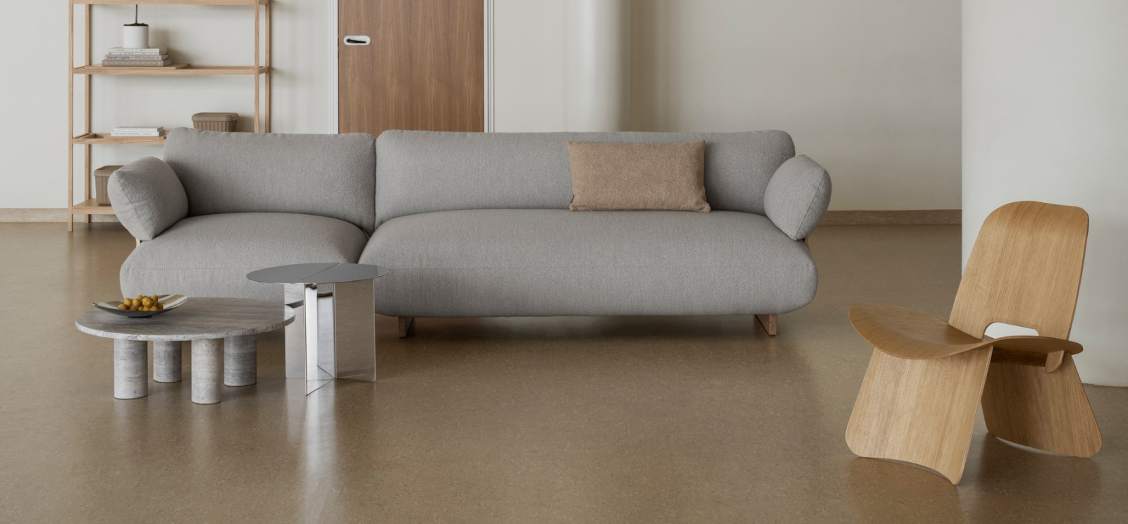Modern living room with a gray sofa, wooden chair, and stylish side tables.
