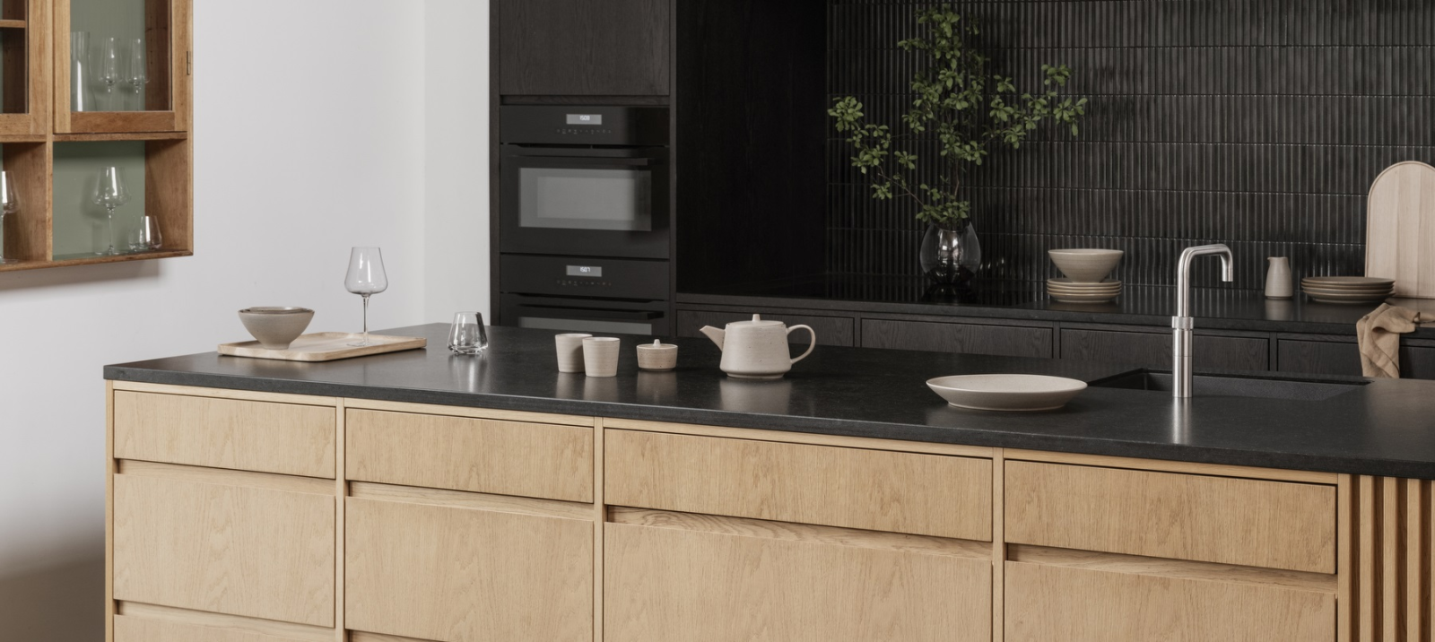 Modern kitchen design featuring a sleek black backsplash and natural wood cabinetry.