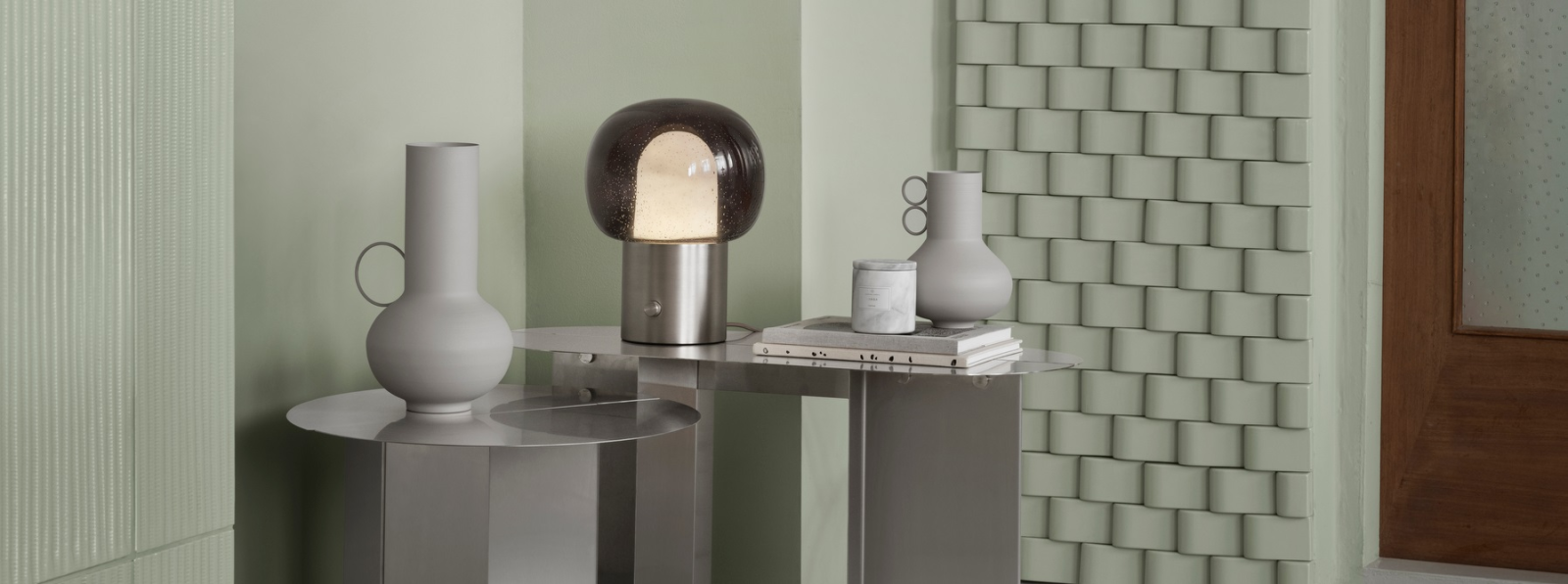 Modern interior decor featuring minimalist vases and a stylish lamp on a sleek table.
