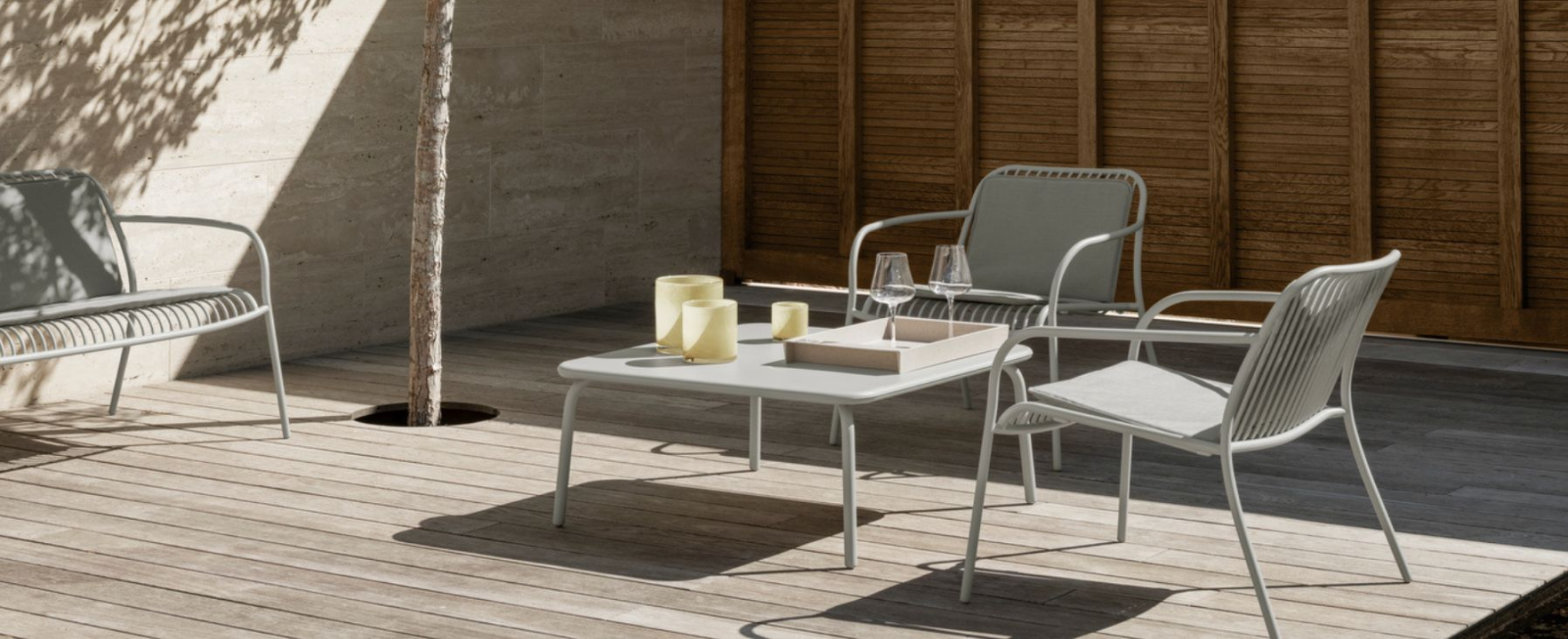Moderne Terrassenmöbel mit Tisch und Stühlen in einem minimalistischen Außenbereich.