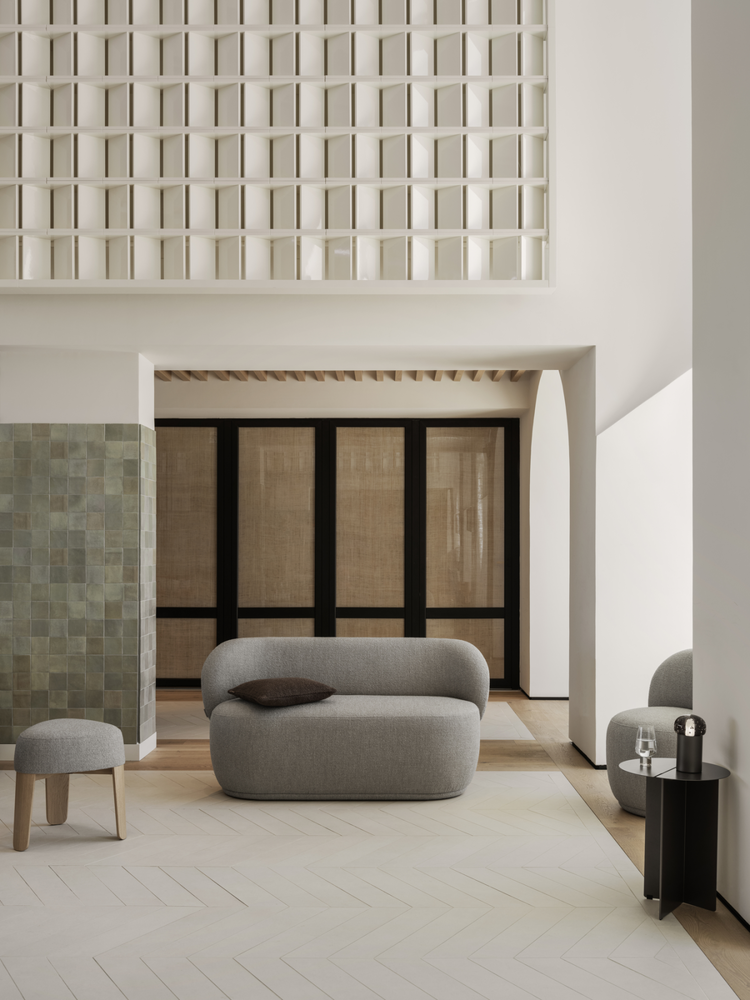 Modern minimalist living room with a curved gray sofa and stylish decor elements.