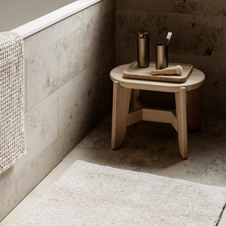 Moderne Badezimmer-Ecke mit Holzstuhl, dekorativen Behältern und Teppich.
