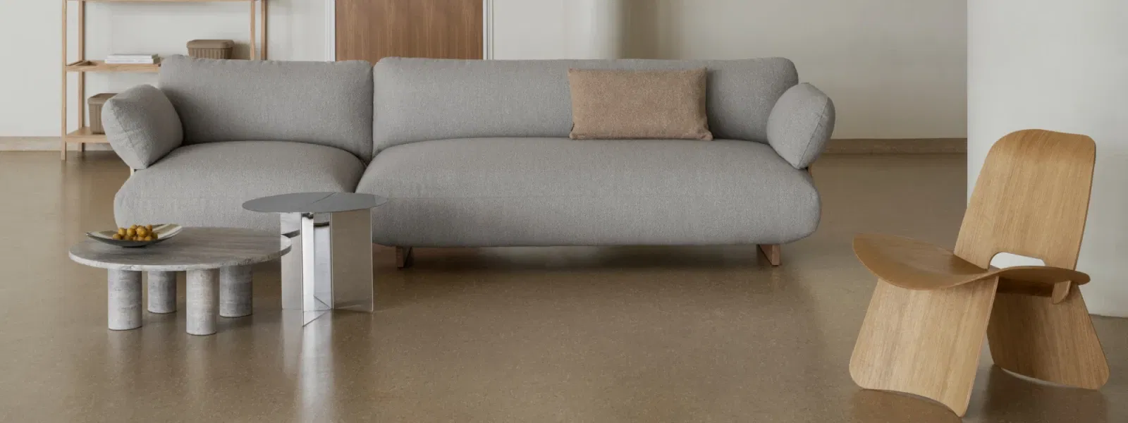 Moderner Wohnraum mit grauem Sofa, Holzstuhl und eleganten Beistelltischen.