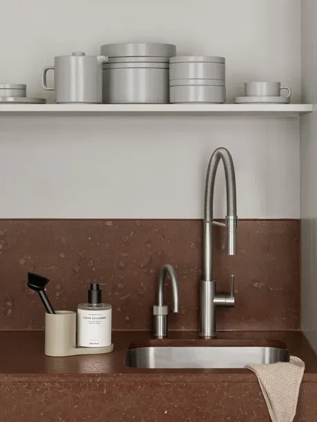 Moderne Küche mit grauen Utensilien und stilvollem Wasserhahn auf braunem Tisch.