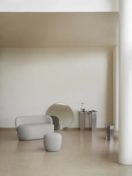 Modern Wohnraum mit grauem Sofa, minimalistischem Tisch und runder Spiegelakzent.