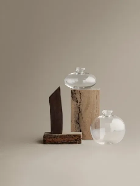 Moderne Dekoration mit Glasvasen und geometrischen Holzobjekten auf neutralem Hintergrund.