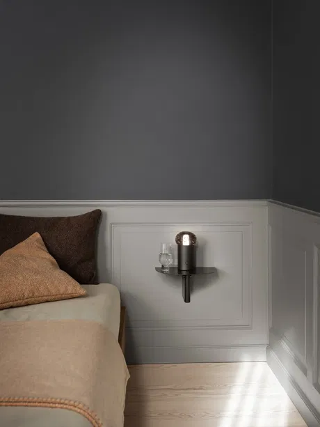 Moderne Wandlampe in stilvollem Schlafzimmer mit beige und dunklen Akzenten.