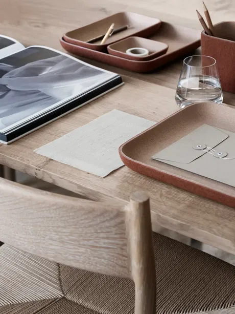 Moderne Tischdekoration mit Geschirr, Zeitschriften und Glas auf Holzoberfläche.