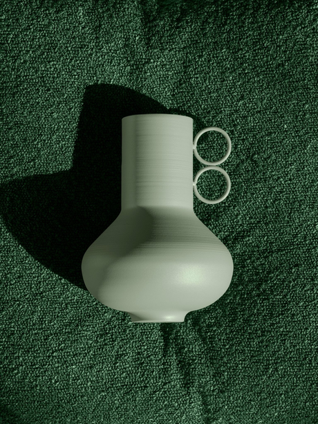 Minimalist green vase with unique handle design on textured background.