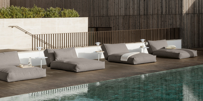 Moderne graue Liegen und Tische am Pool in einer stilvollen Umgebung.