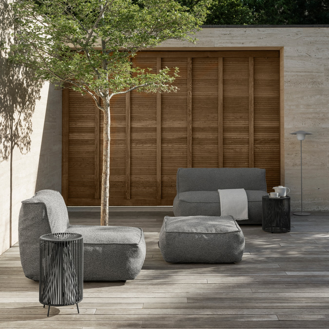 Moderne Gartenmöbel mit einer kleinen Baum und Holzverkleidung im Hintergrund.