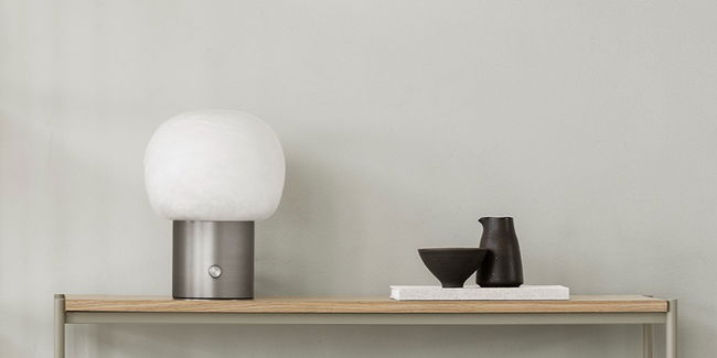 Moderne Tischlampe und dekorative Objekte auf einem minimalistischen Regal.