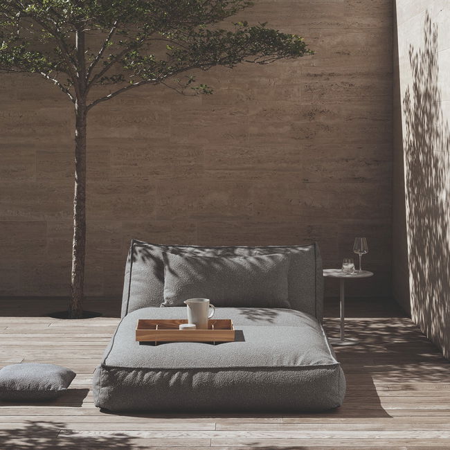 Moderne Liege im Freien mit Tisch, Glas und Baum in einer minimalistischen Umgebung.