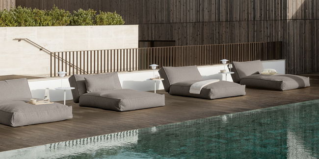 Moderne Lounge-Möbel am Pool mit eleganten Tischen und sanften Farben im Hintergrund.