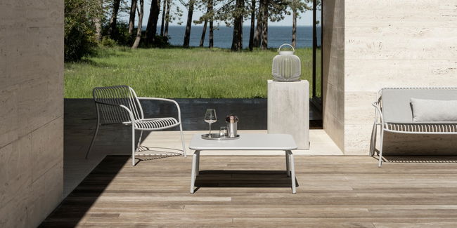 Moderne Terrassengestaltung mit einem Tisch und Stühlen neben einem ruhigen See.